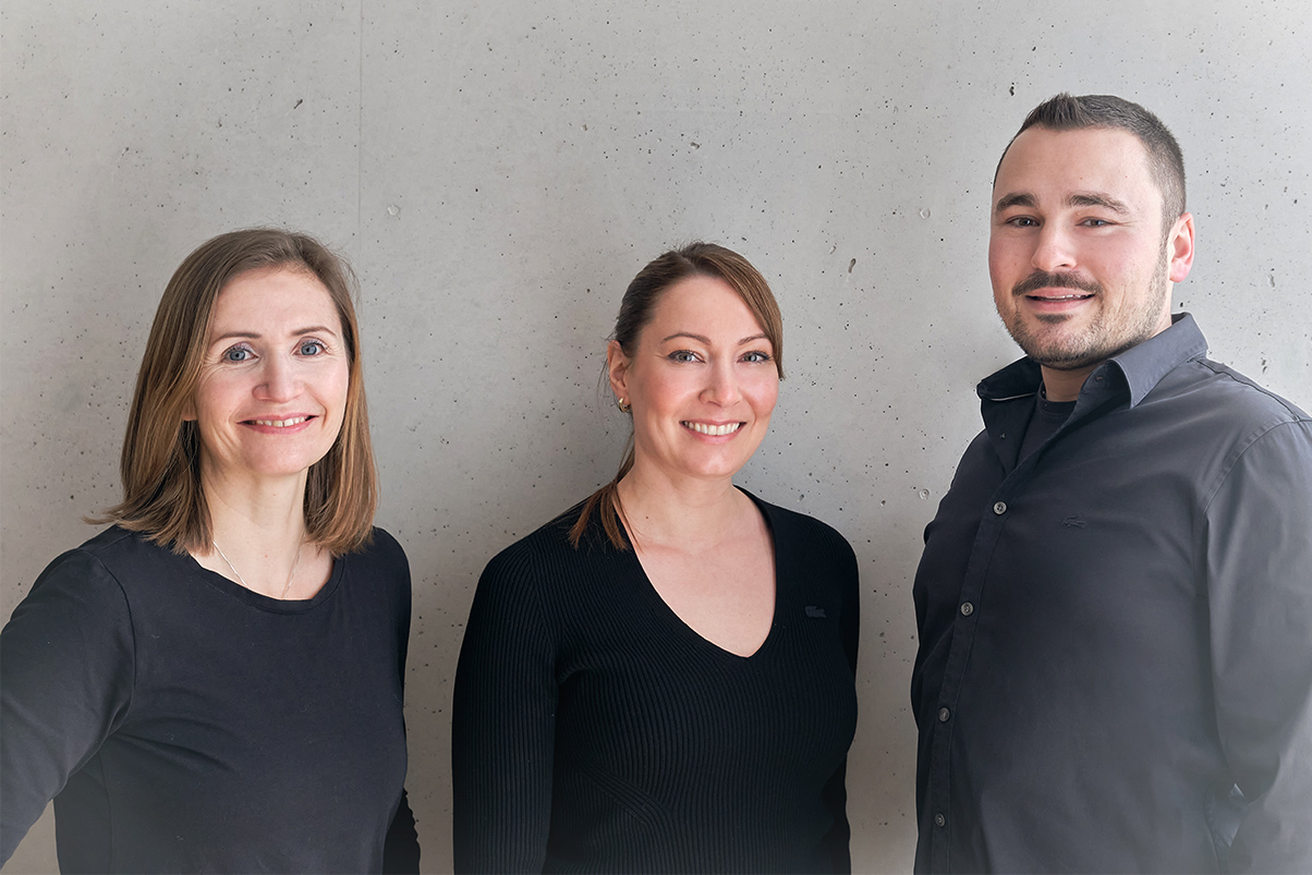 drei architekten stehen gemeinsam vor betonwand