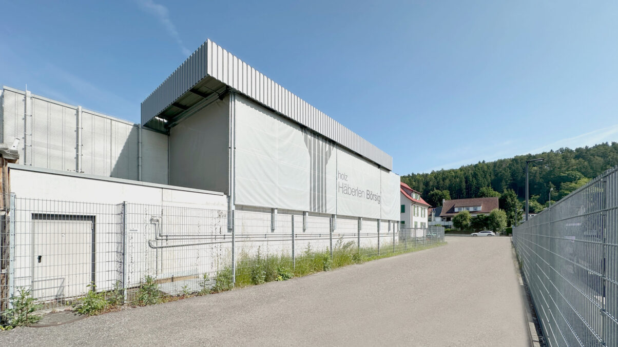 lagerfläche mit holz und angrenzender produktionshalle