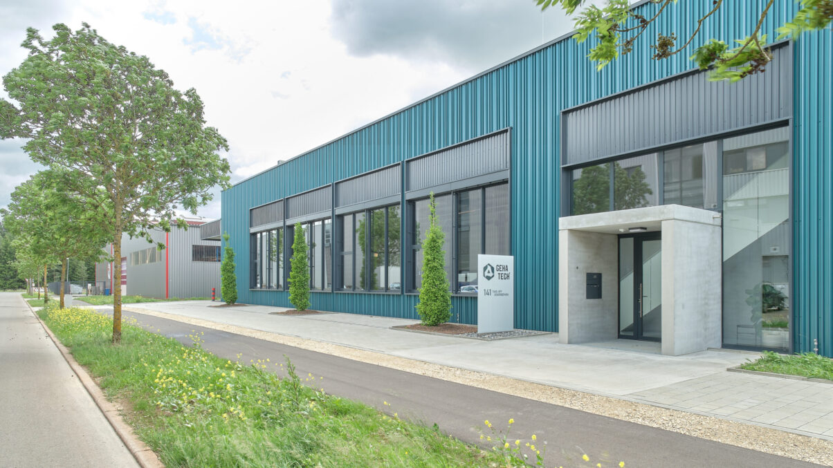 geha tech produktionshalle neuhausen – architektur außen produktionshalle mit grünem metallbau und eingangsbereich