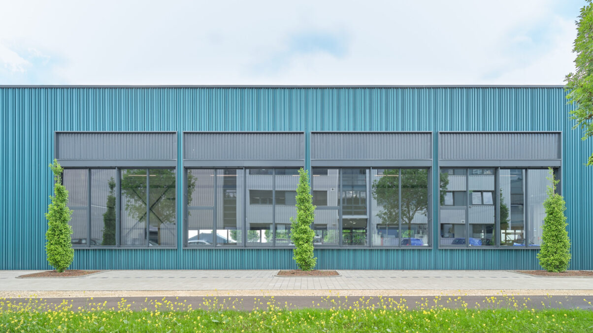 neubau produktionsgebäude neuhausen – hauptfassade moderne industriehalle mit großer glasfront