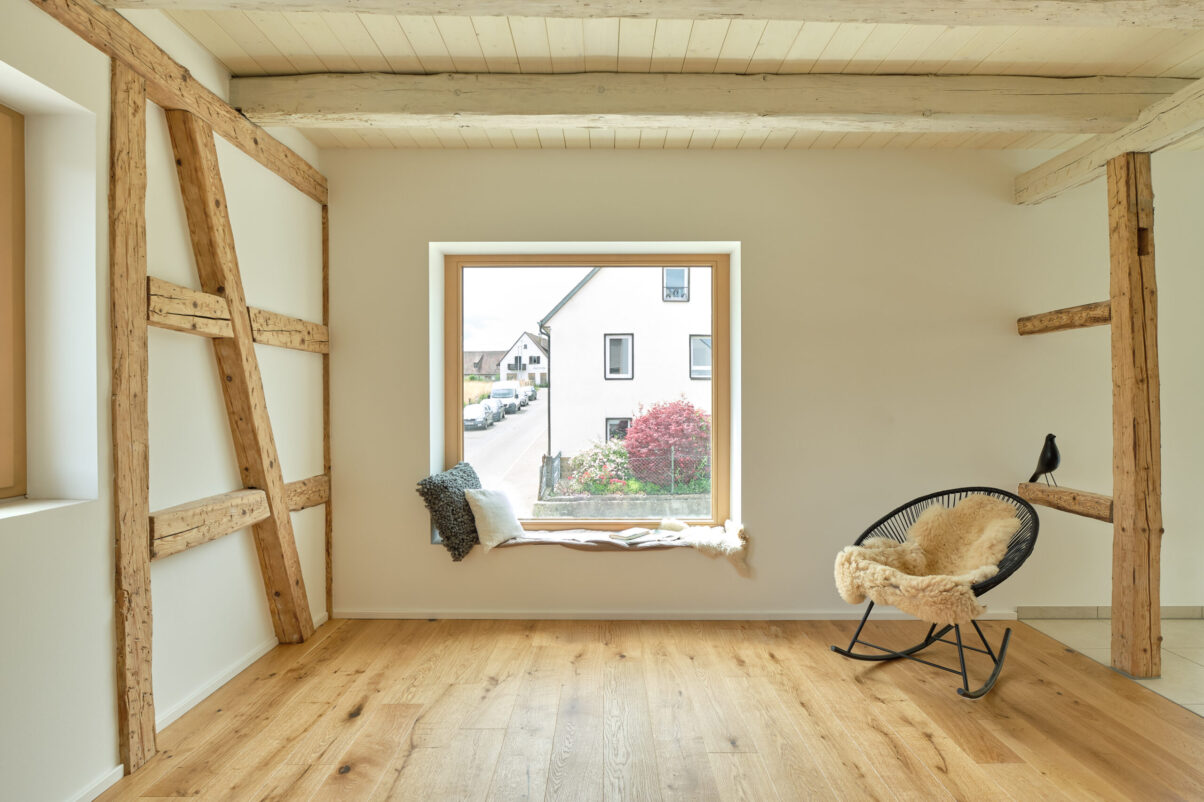 sanierung wohnhaus – wohnzimmer mit sichtfachwerk und sitzfenster wohnraum mit holzboden und sichtbarem fachwerk