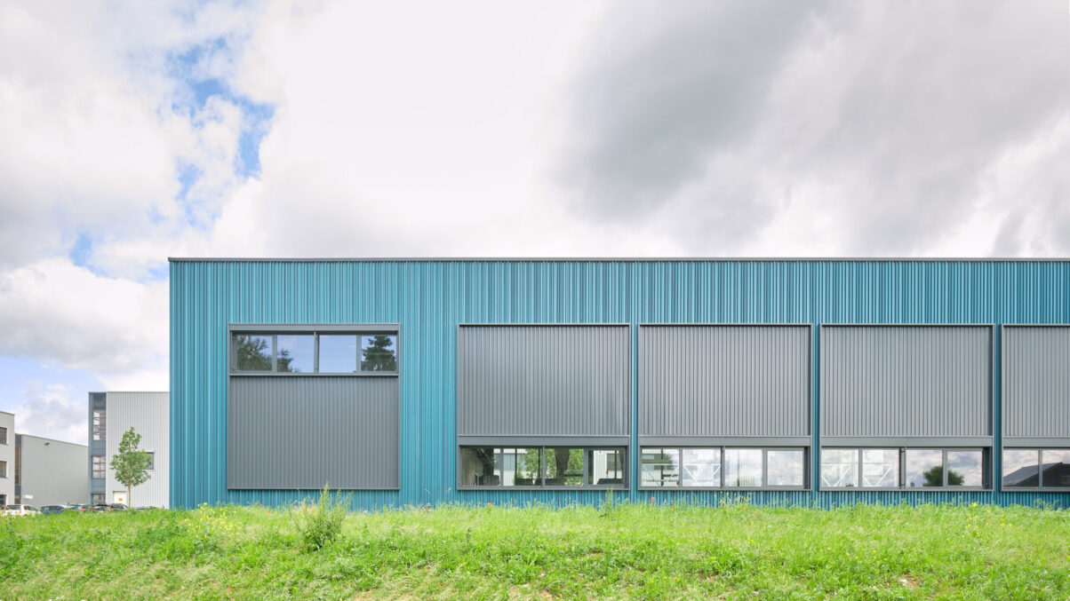 neubau produktionsgebäude neuhausen – hauptfassade moderne industriehalle mit großer glasfront