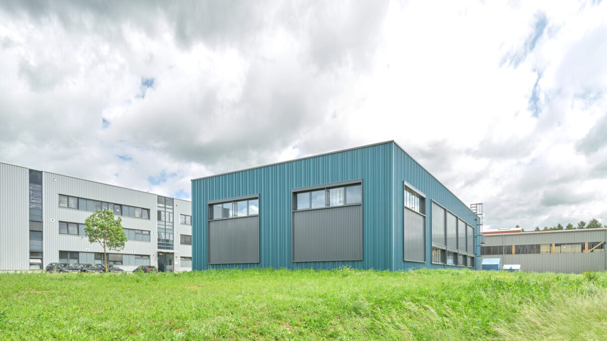 neuhausen produktionshalle – außenansicht südseite produktionshalle mit fenstern und grünfläche