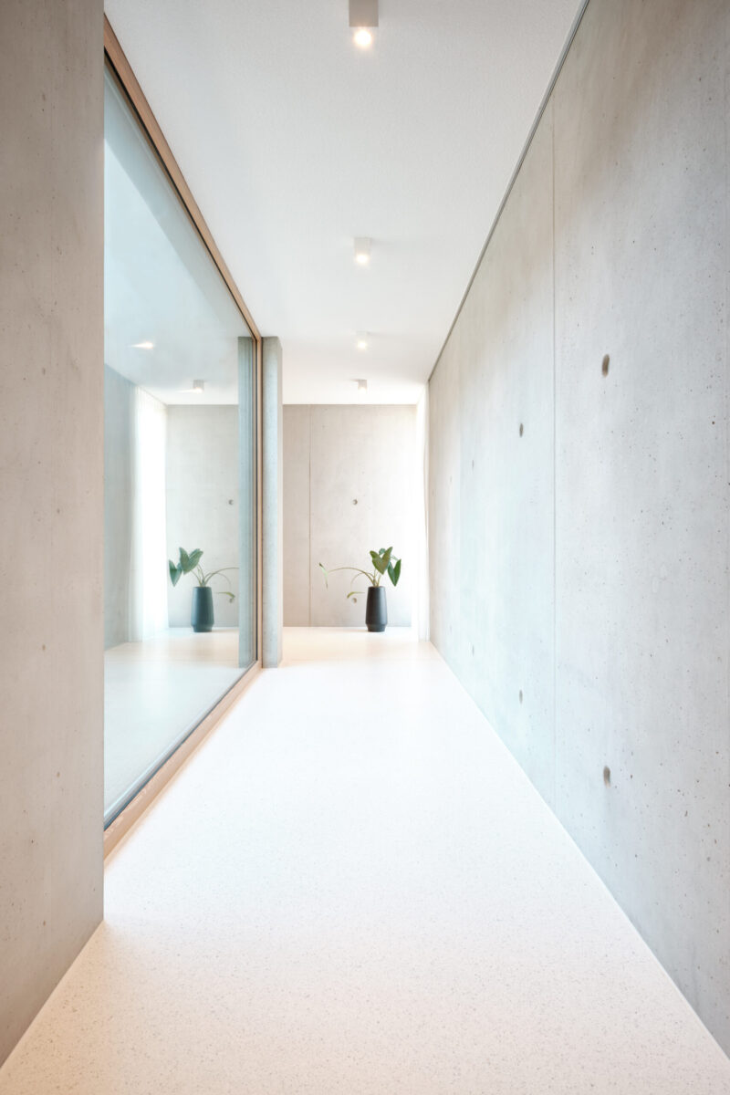neubau einfamilienhaus – moderner flur mit sichtbeton heller flur mit glaswand und sichtbeton