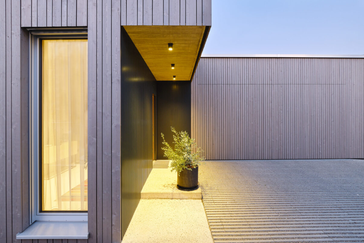 neubau einfamilienhaus – eingangsbereich mit blechfassade betonfassade mit eingangstür und pflanzkübel